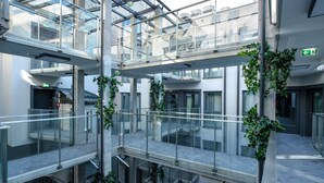 Et atrium med flere niveauer, glasgelændere og grøn vegetation.