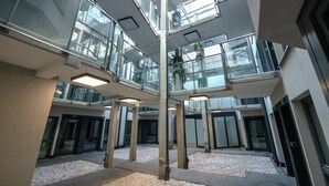 En flerlags atrium med glasgelændere, betonstolper og en grusgulv.