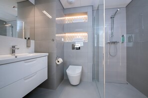 Une salle de bain moderne avec une douche à parois de verre, un lavabo blanc et des toilettes.
