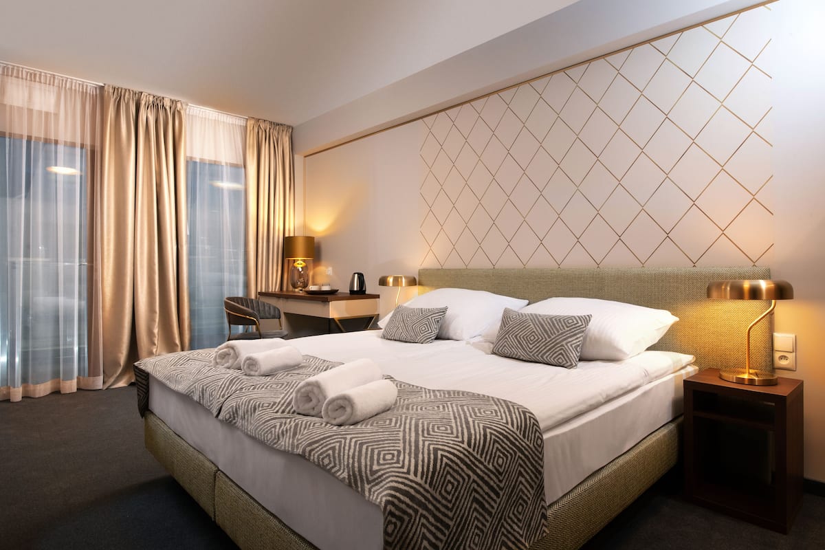 A hotel room with a large bed, two bedside tables, a desk, and a chair.