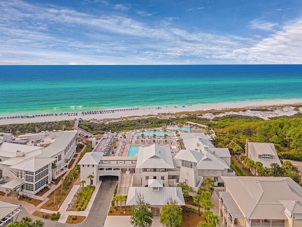 A resort with multiple buildings, a swimming pool, and a beach view.