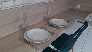 Una cocina moderna con dos platos blancos, dos copas de vino y una silla verde.
