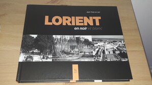 Un libro titulado “Lorien en noir et blanc” de Jean-Yves Le Lan, con fotografías en blanco y negro de un paisaje urbano y un barco.
