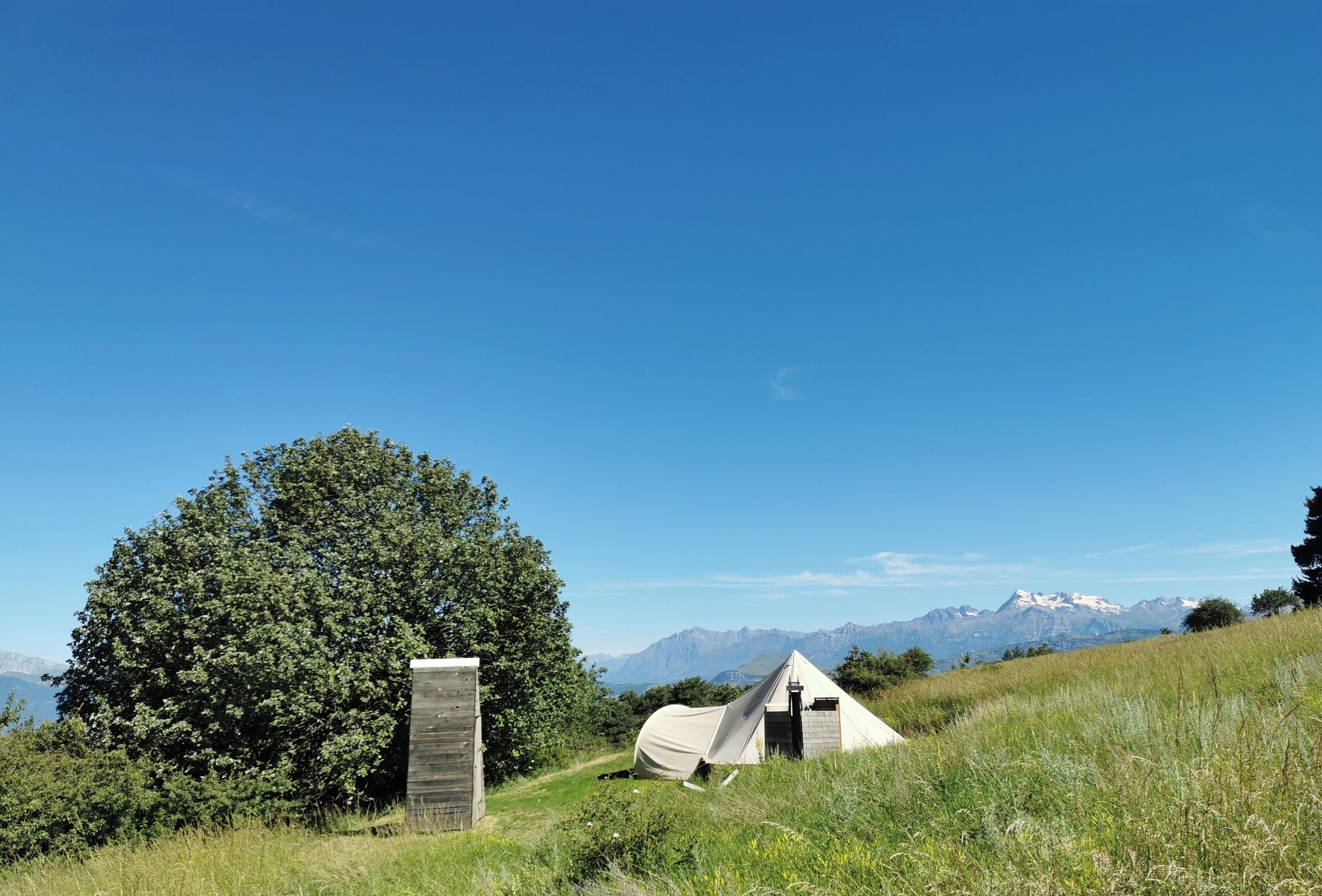 A tented accommodation with a view of mountains in the background.
