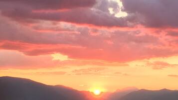 A sunset over a mountain range with clouds in the sky.