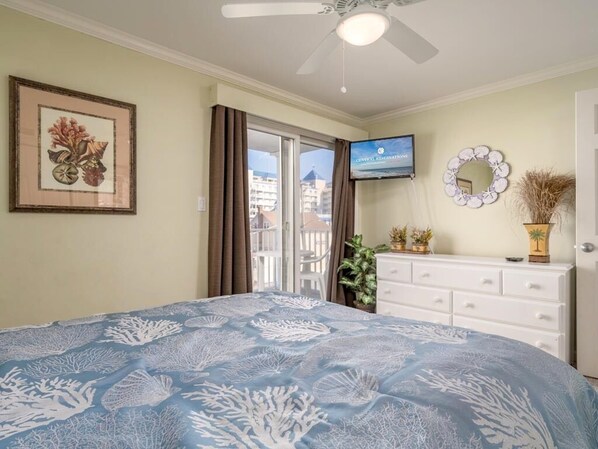 A bedroom with a bed, a television, a dresser, and a balcony with a view of buildings.