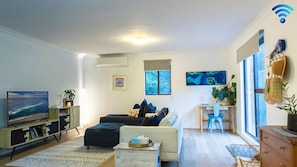 Relax in this stylish living room with a flat-screen TV, comfortable sofa, and a beautiful view of the surrounding trees.