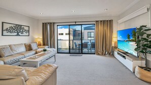 A modern living room with a sofa, a coffee table, a TV, and a balcony with a view of the sea. - Starfish Sands in Cowes (Cowes)