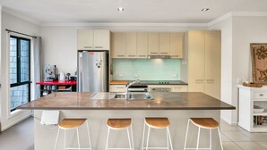 A modern kitchen with a large island, bar stools, and a coffee machine. - Starfish Sands in Cowes (Cowes)