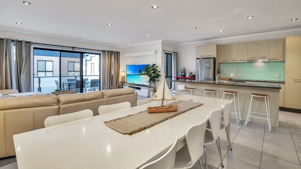 A modern living room with a sofa, dining table, and kitchen area with bar stools. - Starfish Sands in Cowes (Cowes)