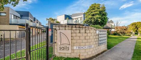 A gated residential area with a sign for 'Sails on Beach Street' and a mailbox.