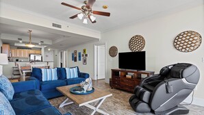 Un salon avec un canapé bleu, un fauteuil massant, une table basse en bois et un téléviseur.