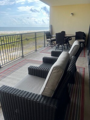 Relax on the balcony with ocean views, a wicker lounge set, and a small table for two.