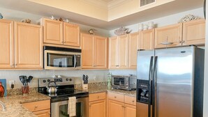 A modern kitchen with wooden cabinets, stainless steel appliances, granite countertops, and a built-in oven.
