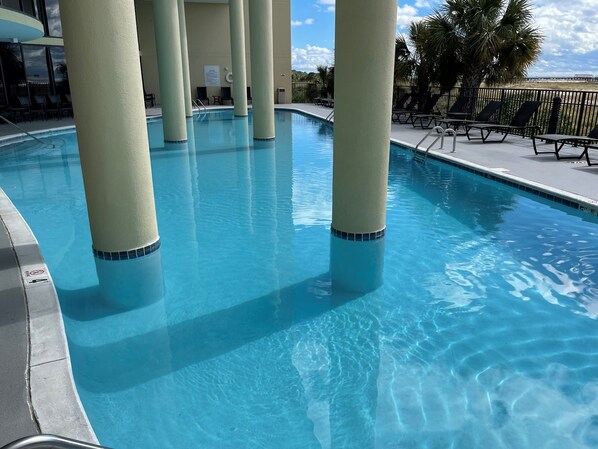 Relax by the pool surrounded by pillars, with lounge chairs nearby.