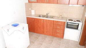 Uma cozinha compacta com armários de madeira, pia, forno pequeno e máquina de lavar.