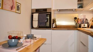 A modern kitchen with white cabinets, a wooden countertop, and a built-in oven. - Cozy 1 Bedroom Home Near the City Centre (Edinburgh)