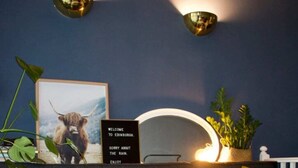 A modern living room with a grey sofa, a wooden coffee table with croissants, and a framed picture of a bull. - Cozy 1 Bedroom Home Near the City Centre (Edinburgh)