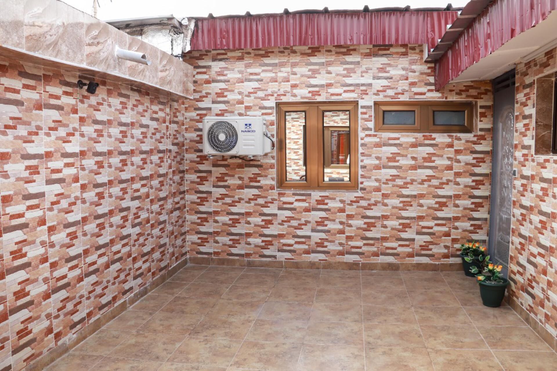 Un patio empedrado con una ventana y un equipo de aire acondicionado.