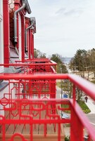 A red metal staircase leading to a building with a view of the sea.