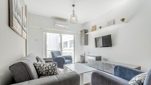 Ein modernes Wohnzimmer mit grauen Sofas, einem Couchtisch und einem an der Wand befestigten Flachbildfernseher.