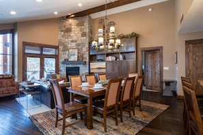 A dining area with a stone fireplace, wooden furniture, and a chandelier.