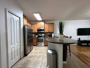 A modern kitchen with a central island, stainless steel appliances, and wooden cabinets. - 1056 Orlando Villa: Private Pool and Game Room (Davenport)