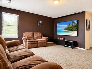 A living room with a recliner, a flat-screen TV, and a wall-mounted console. - 1056 Orlando Villa: Private Pool and Game Room (Davenport)