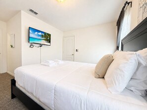 Una habitación de hotel con una cama, un televisor en la pared y una puerta.