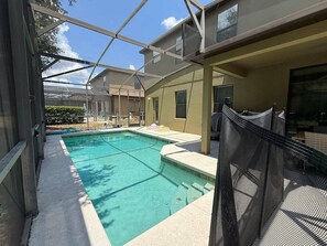 A swimming pool with a covered area, surrounded by a building with a balcony.
