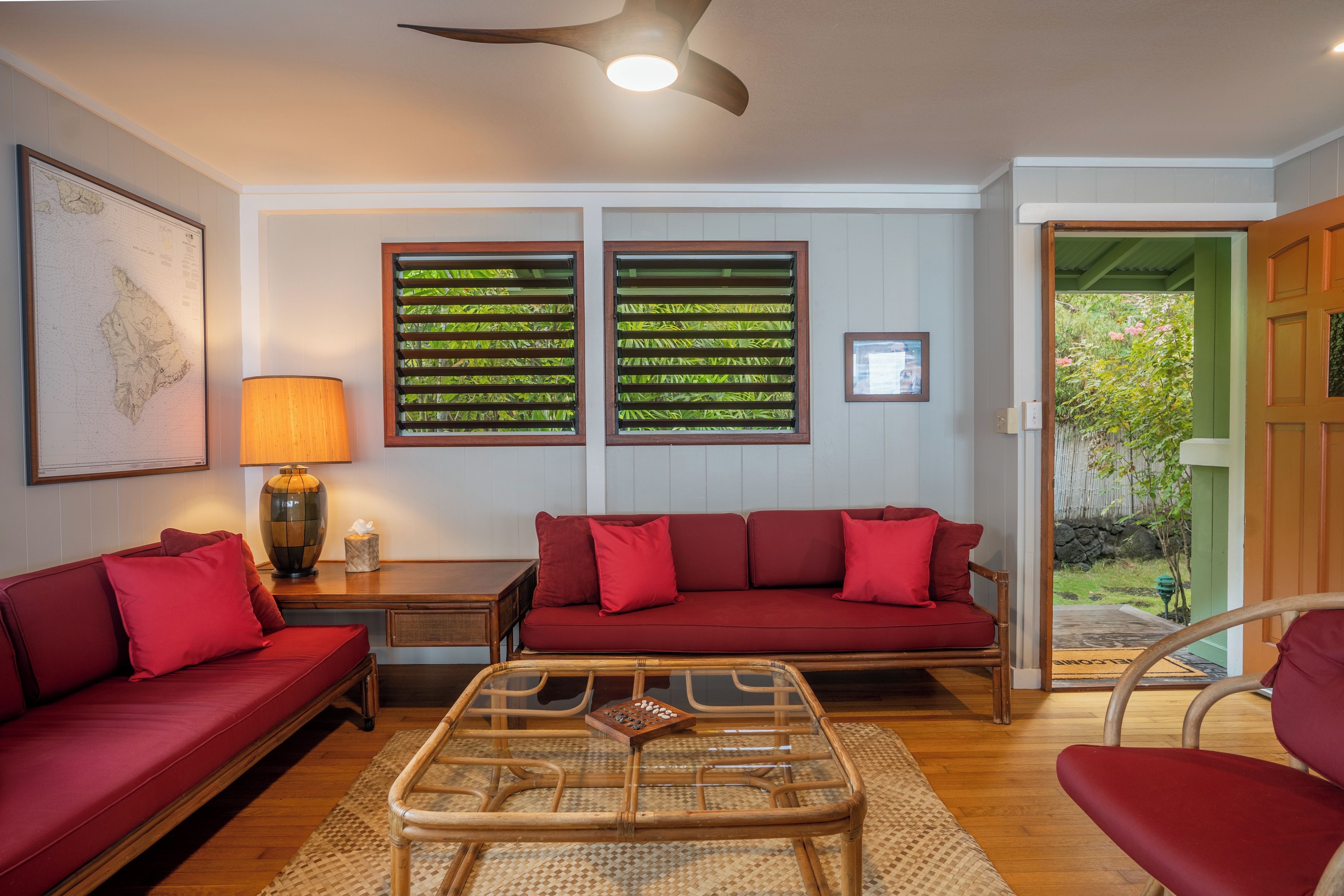 A living room with a red sofa, a glass coffee table, and a wooden floor.