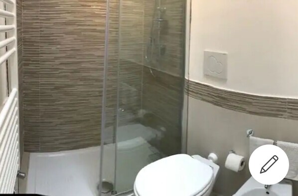 Une salle de bain avec une douche à parois de verre, des toilettes et un bidet.