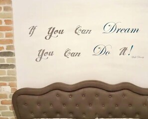 Une citation inspirante sur un mur, avec une tête de lit capitonnée.