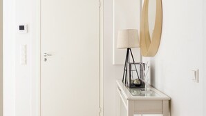 A minimalist room with a white door, a console table with a lamp, and a mirror. - Stylish Bright 42m2 Studio with Balcony (Helsinki)