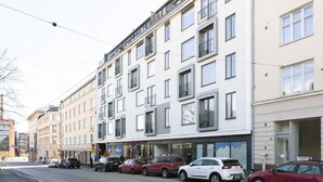 A multi-story building with a row of parked cars on the street in front. - Stylish Bright 42m2 Studio with Balcony (Helsinki)