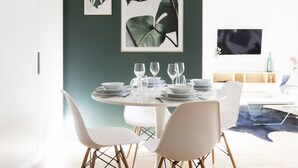 A dining area with a round table set for four, white chairs, and framed artwork on the wall. - Stylish Bright 42m2 Studio with Balcony (Helsinki)