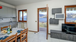 A modern kitchen with a dining area, a TV, and a balcony with a scenic view.
