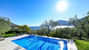 A swimming pool with a clear view of the sea and mountains in the background.