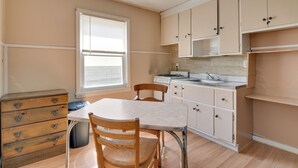 Una cocina con armarios de madera, encimera blanca y ventana con persianas.