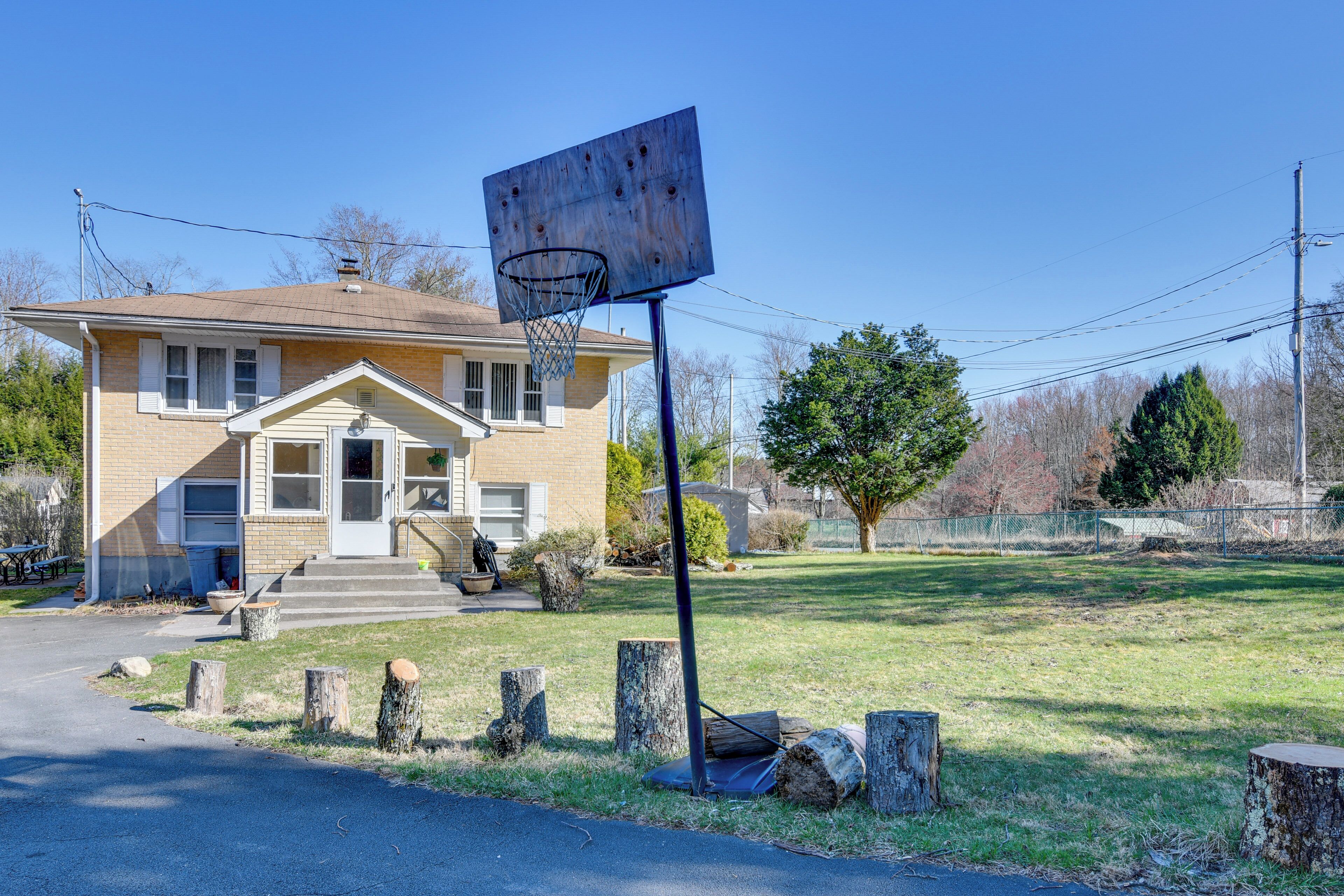 A residential house with a basketball hoop in the front yard.
