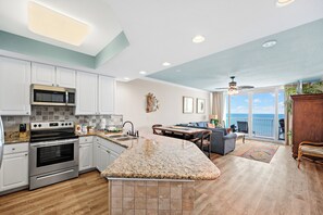 A modern kitchen with granite countertops, stainless steel appliances, and a dining area with a view of the ocean.
