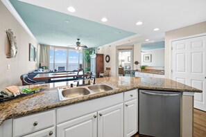 A kitchen with granite countertops, white cabinets, and a dishwasher.