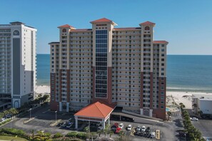 A high-rise hotel with multiple floors, a central atrium, and a beach view.