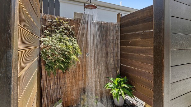 A wooden fence with a vertical water feature and a potted plant.