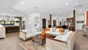 A spacious living room with a large sofa set, a coffee table, and a dining area with bar stools.