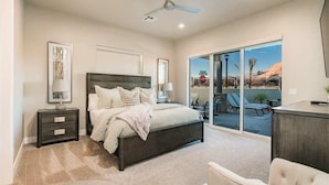 A bedroom with a large bed, a nightstand, a chair, and a view of the outdoors through a sliding glass door. - O-29&30| 2 Homes! Private Pool & Hot Tubs * Views (Santa Clara)