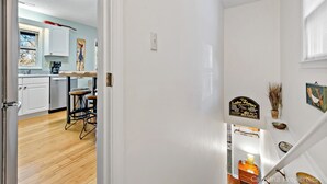 Una cucina con mobili bianchi, una macchina da caffè e un quadro appeso al muro.