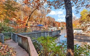 A wooden boardwalk over a body of water, surrounded by trees with autumn foliage.