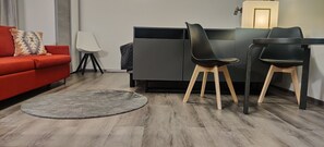 A modern living room with a red sofa, two black chairs, a round rug, and a grey sofa. - Kuukkeli Apartments Inari (Inari)