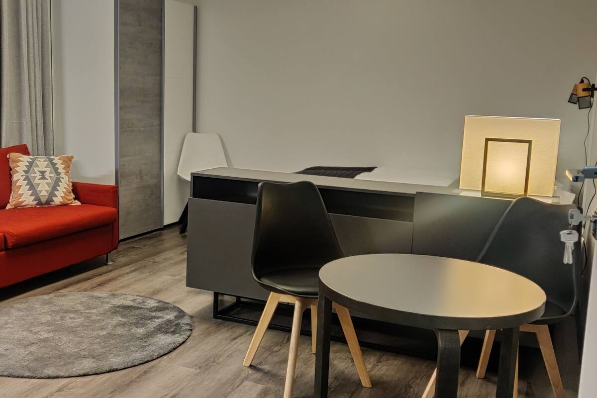 A modern room with a red sofa, a desk with a chair, and a small round table.